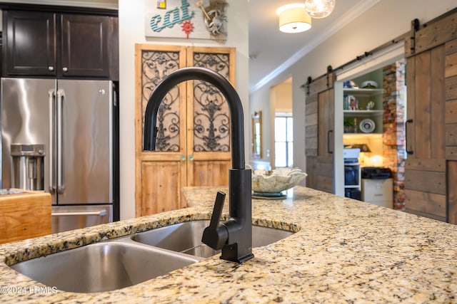 kitchen with sink, crown molding, high quality fridge, a barn door, and light stone countertops