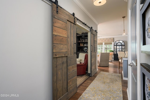 corridor featuring dark hardwood / wood-style flooring, ornamental molding, and a barn door