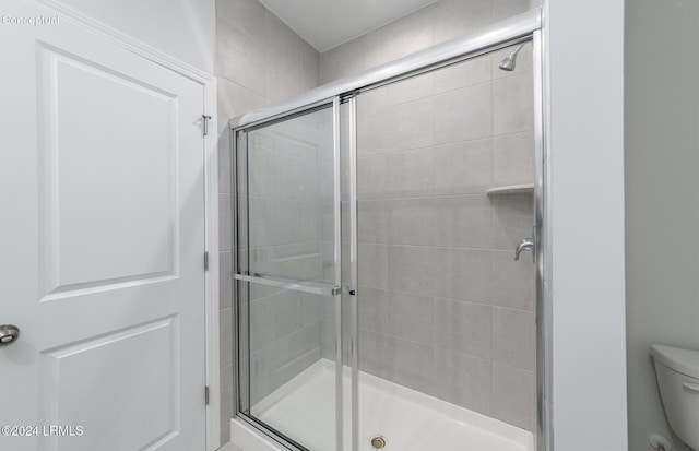 bathroom featuring toilet and a shower with shower door