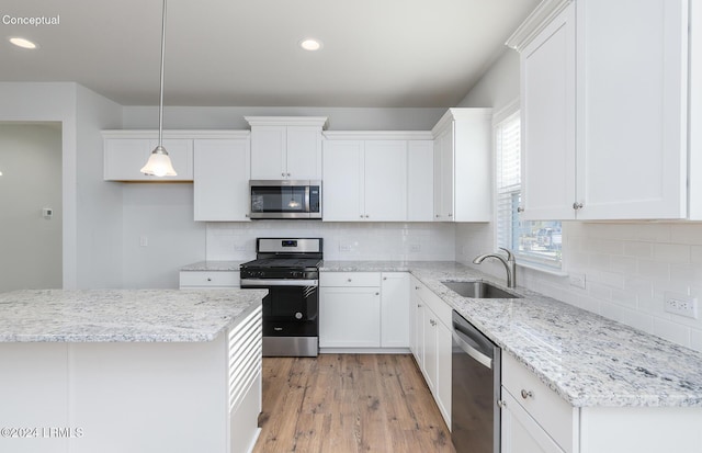 kitchen with pendant lighting, appliances with stainless steel finishes, sink, and white cabinets