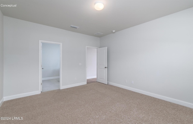 unfurnished bedroom with a spacious closet, light colored carpet, and a closet