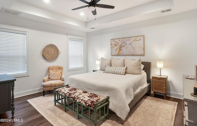 bedroom featuring dark hardwood / wood-style flooring, a raised ceiling, and ceiling fan