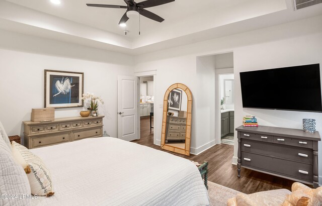 bedroom featuring ensuite bathroom, dark hardwood / wood-style floors, ceiling fan, and a tray ceiling