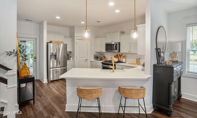 kitchen with appliances with stainless steel finishes, pendant lighting, white cabinetry, backsplash, and kitchen peninsula