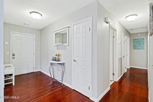 entryway featuring a textured ceiling, wood finished floors, and baseboards