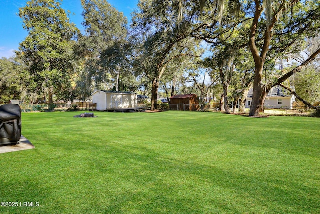 view of yard featuring a storage shed, a fenced backyard, and an outdoor structure