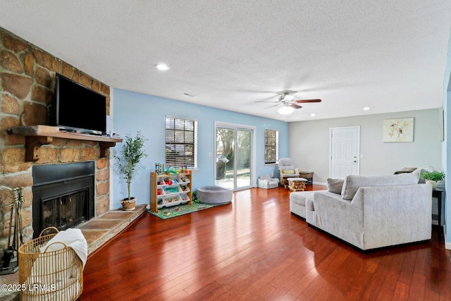 living room featuring a ceiling fan, wood-type flooring, a textured ceiling, a fireplace, and recessed lighting