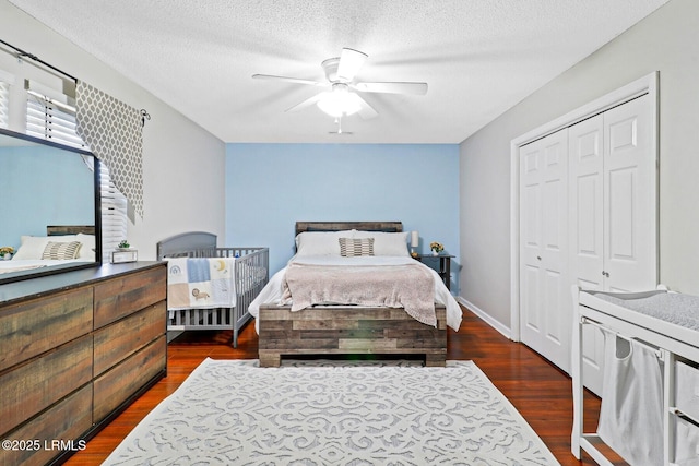 bedroom featuring dark wood-style flooring, a closet, ceiling fan, a textured ceiling, and baseboards