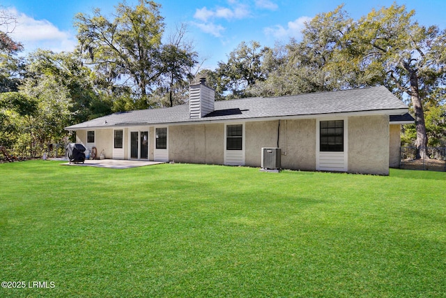 rear view of property with a chimney, a lawn, a patio area, and central air condition unit