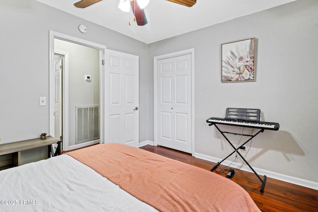 bedroom featuring dark wood-style flooring, a ceiling fan, visible vents, baseboards, and a closet