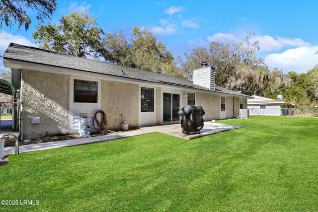 back of property with a yard, a chimney, fence, and stucco siding