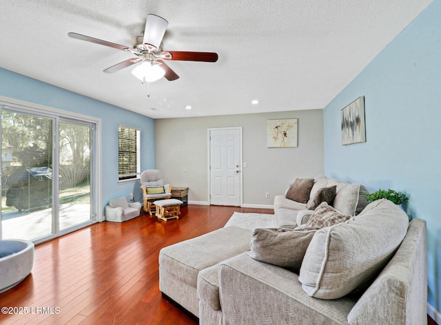 living area with ceiling fan, a textured ceiling, baseboards, and hardwood / wood-style flooring