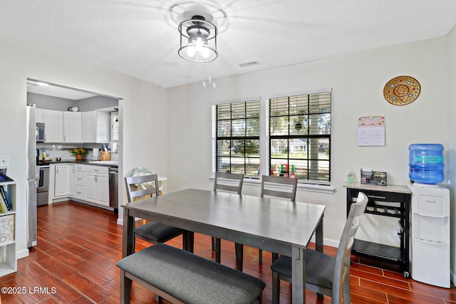 dining area featuring wood finish floors, a textured ceiling, and baseboards