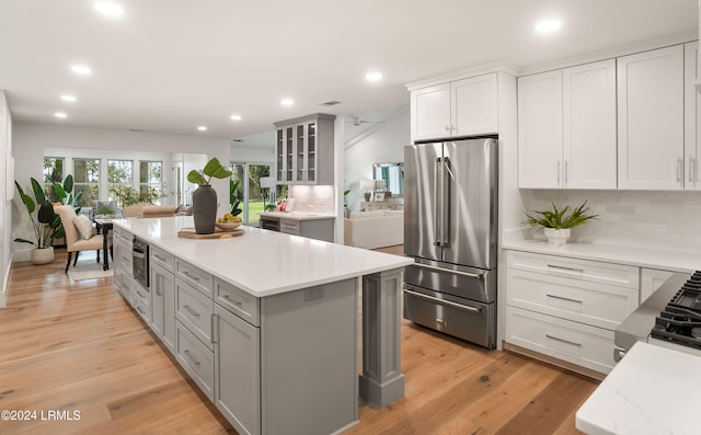 kitchen featuring gray cabinetry, tasteful backsplash, high end refrigerator, a center island, and light hardwood / wood-style flooring