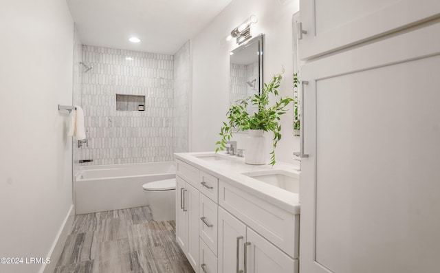 full bathroom featuring vanity, tiled shower / bath, and toilet