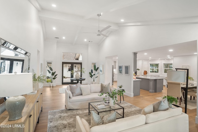 living room with beam ceiling, ceiling fan, light wood-type flooring, and high vaulted ceiling