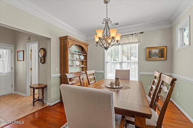 dining space with crown molding, light hardwood / wood-style flooring, and a chandelier