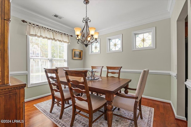 dining area featuring ornamental molding, hardwood / wood-style floors, and a notable chandelier