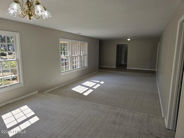 carpeted empty room with a notable chandelier