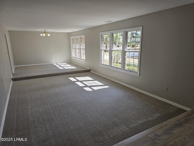 spare room with carpet and a chandelier