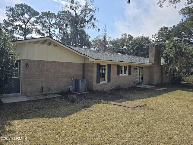 rear view of property featuring central AC and a lawn