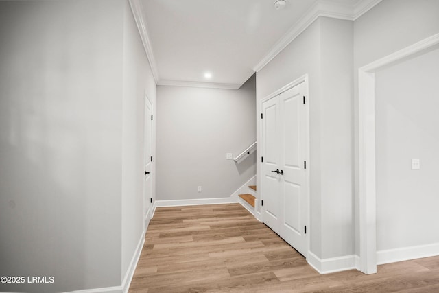 hallway with light wood-style floors, crown molding, and baseboards