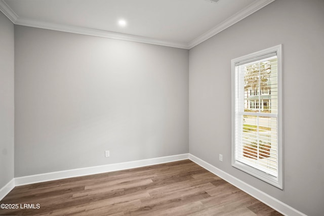 spare room featuring baseboards, wood finished floors, and ornamental molding