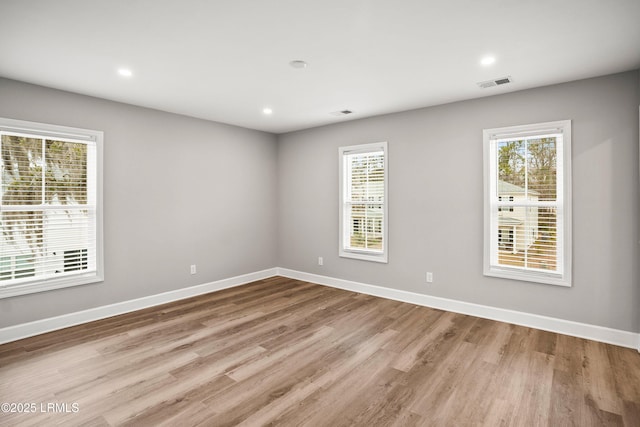 spare room featuring plenty of natural light, visible vents, and baseboards