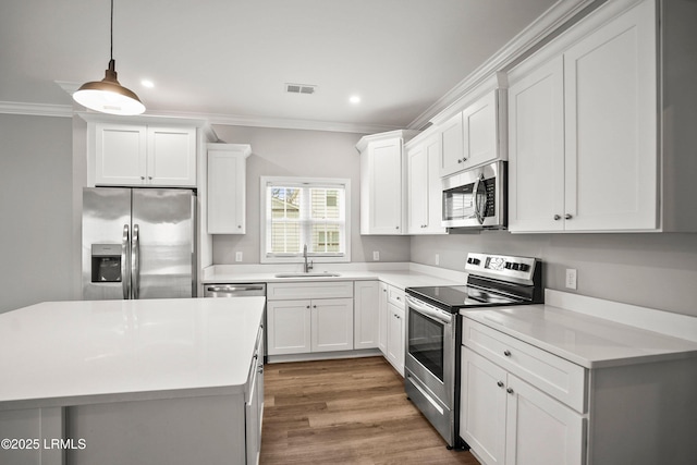 kitchen with crown molding, stainless steel appliances, light countertops, visible vents, and a sink