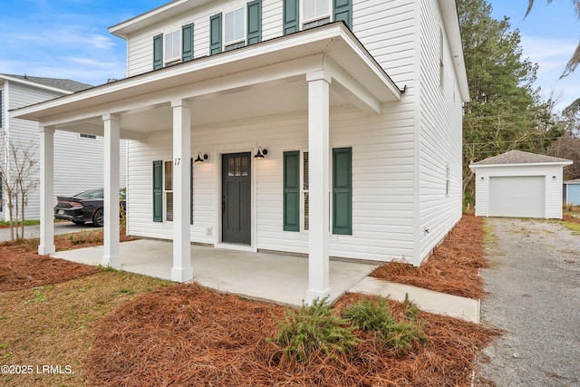 exterior space featuring gravel driveway, covered porch, a detached garage, and an outdoor structure