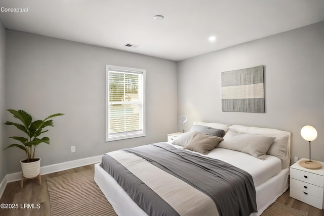 bedroom with visible vents, baseboards, and wood finished floors