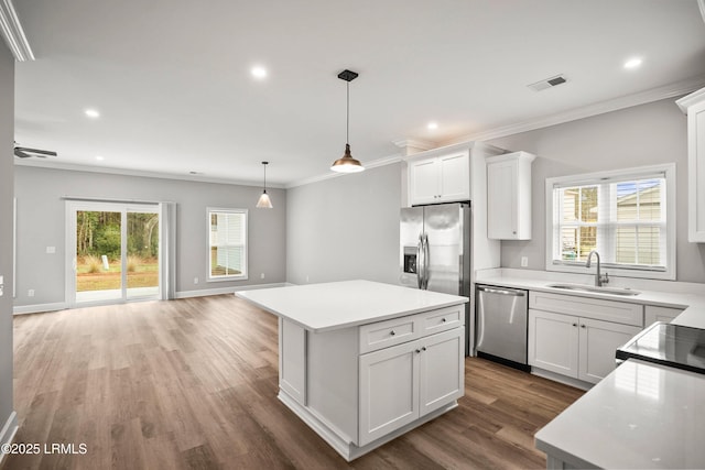 kitchen with stainless steel appliances, visible vents, a kitchen island, a sink, and wood finished floors