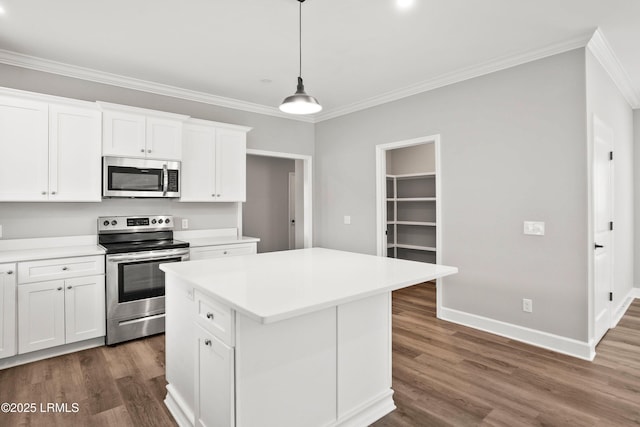 kitchen with dark wood-style floors, stainless steel appliances, ornamental molding, white cabinets, and a kitchen island