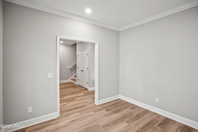 spare room with light wood-style floors, stairway, baseboards, and ornamental molding