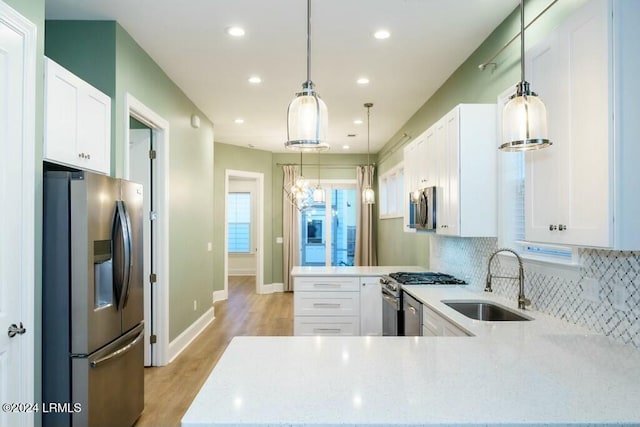 kitchen with white cabinetry, appliances with stainless steel finishes, sink, and kitchen peninsula