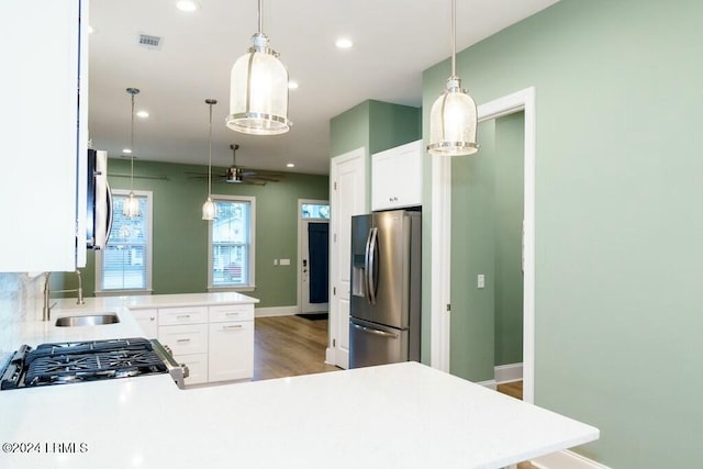 kitchen featuring sink, decorative light fixtures, white cabinets, and stainless steel refrigerator with ice dispenser