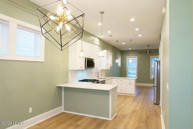 kitchen with tasteful backsplash, light hardwood / wood-style flooring, kitchen peninsula, stainless steel appliances, and white cabinets