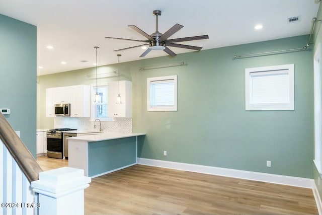 kitchen with pendant lighting, sink, white cabinetry, stainless steel appliances, and decorative backsplash