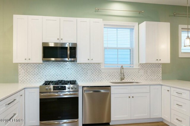 kitchen with tasteful backsplash, appliances with stainless steel finishes, sink, and white cabinets