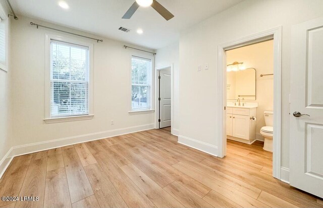 unfurnished bedroom with sink, ensuite bath, ceiling fan, and light wood-type flooring