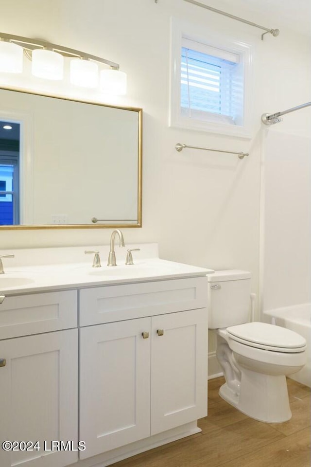 full bathroom with shower / bath combination, vanity, hardwood / wood-style floors, and toilet