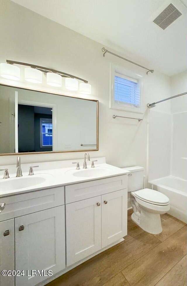 full bathroom featuring wood-type flooring, bathing tub / shower combination, vanity, and toilet