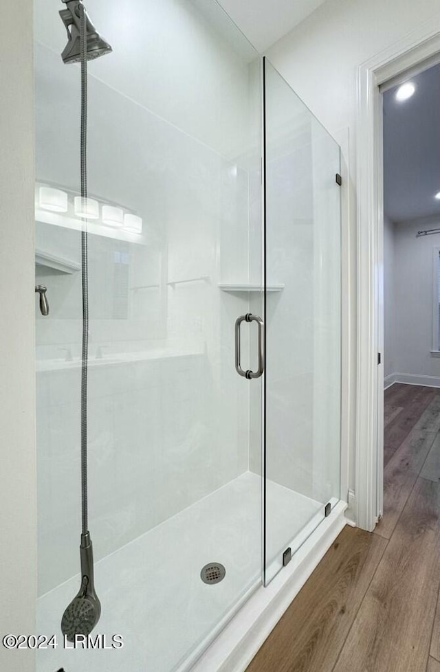 bathroom with a shower with door and hardwood / wood-style floors