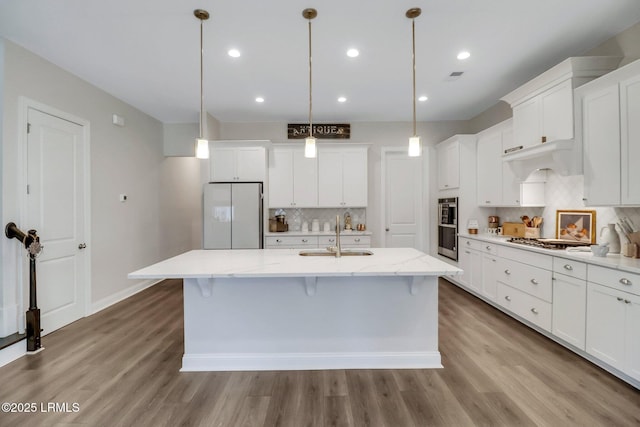 kitchen featuring white cabinetry, hanging light fixtures, an island with sink, and appliances with stainless steel finishes