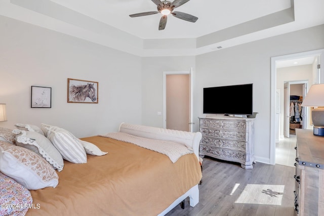 bedroom featuring ceiling fan, a raised ceiling, and hardwood / wood-style floors