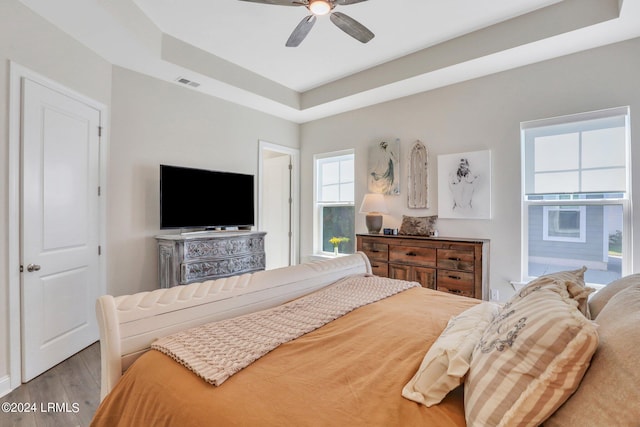 bedroom featuring a tray ceiling, wood-type flooring, and ceiling fan