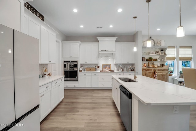 kitchen featuring stainless steel appliances, sink, white cabinets, and decorative light fixtures