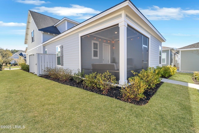 view of side of property featuring a sunroom and a lawn