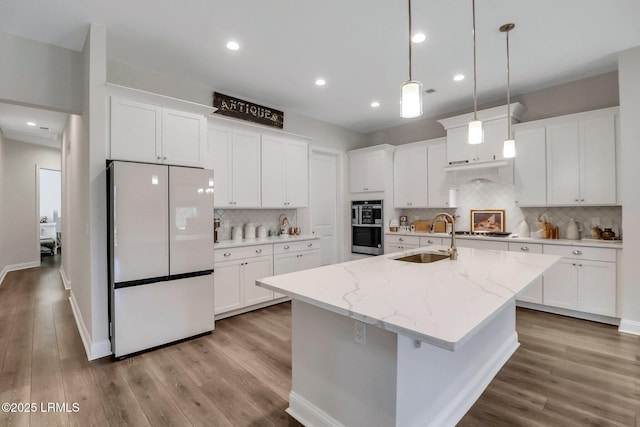 kitchen featuring sink, white cabinetry, a center island with sink, appliances with stainless steel finishes, and light stone countertops