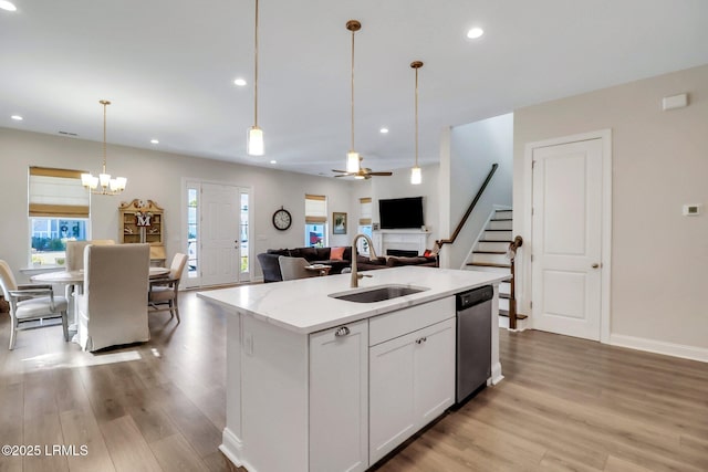 kitchen featuring an island with sink, sink, white cabinets, hanging light fixtures, and stainless steel dishwasher